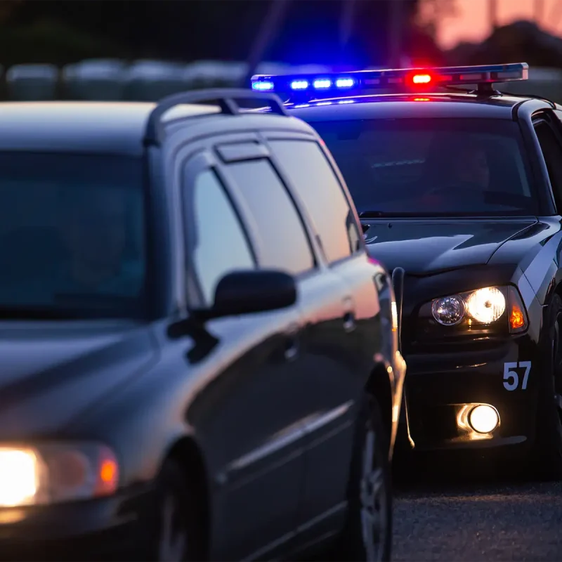 A car that is pulled over by the police for a traffic violation at dusk